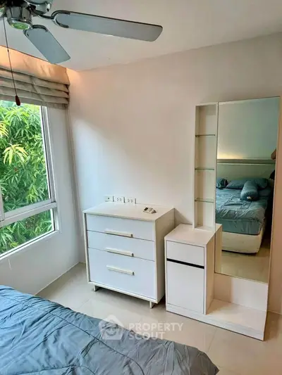 Cozy bedroom with modern furniture and large window overlooking greenery.