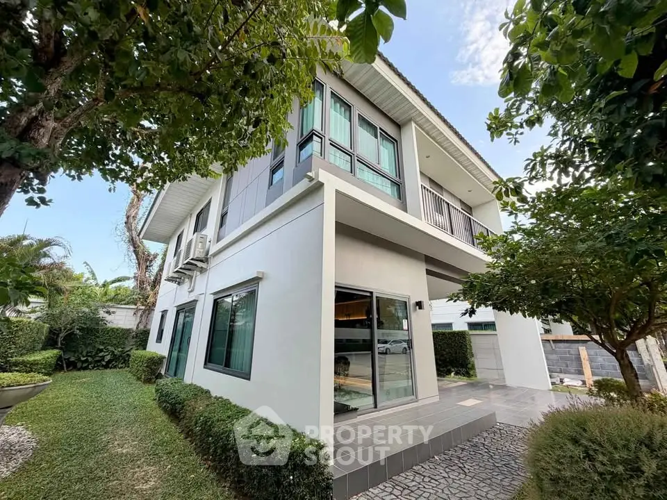 Modern two-story house with lush garden and large windows, showcasing contemporary architecture and serene outdoor space.
