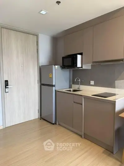 Modern compact kitchen with sleek cabinetry and integrated appliances in a stylish apartment.