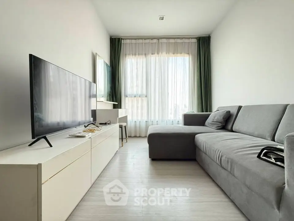 Modern living room with sleek gray sofa and large flat-screen TV