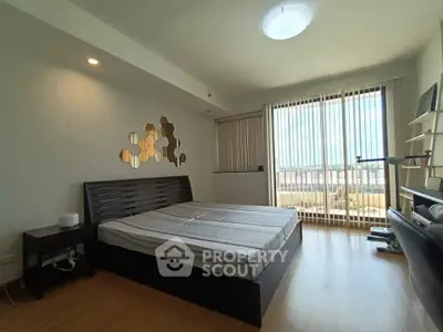 Spacious bedroom with modern decor and large windows offering natural light
