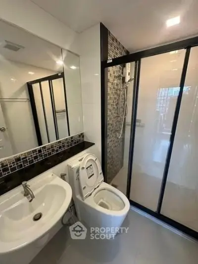 Modern bathroom with sleek shower and stylish sink in contemporary apartment.