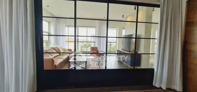 Modern living room with large windows and stylish furniture in a high-rise apartment.