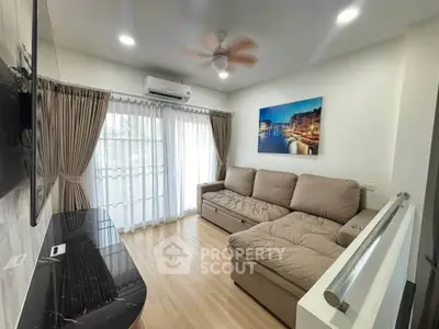 Cozy living room with sectional sofa and modern decor, featuring large windows and natural light.