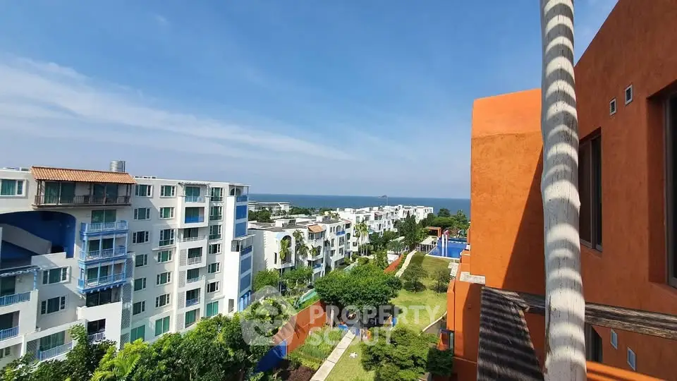 Stunning coastal view from modern apartment complex with lush gardens and vibrant architecture.