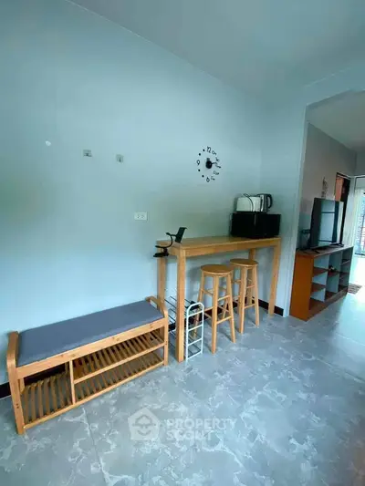 Modern interior with stylish furniture and wall clock, featuring a cozy seating area and sleek TV setup.
