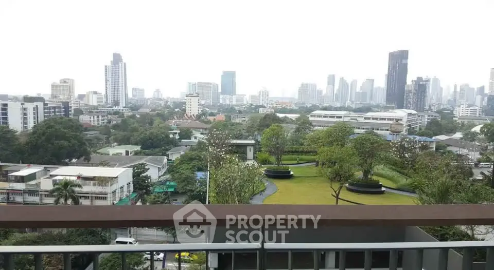 Stunning cityscape view from a high-rise balcony overlooking lush green spaces and urban skyline.