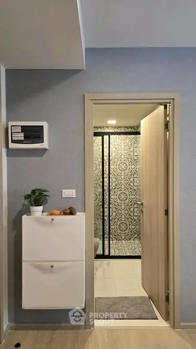 Stylish modern bathroom entrance with patterned tiles and sleek storage solutions.