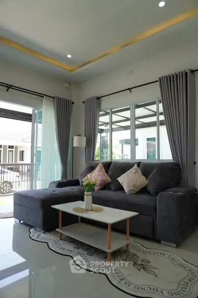 Modern living room with stylish gray sofa and large windows