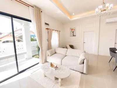 Elegant living room with modern decor and large windows opening to a balcony, featuring a cozy sofa and stylish chandelier.