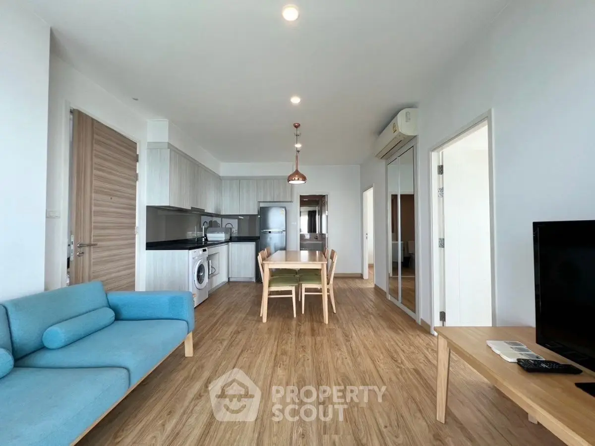 Modern open-plan living room with sleek kitchen and stylish furnishings in a bright apartment.