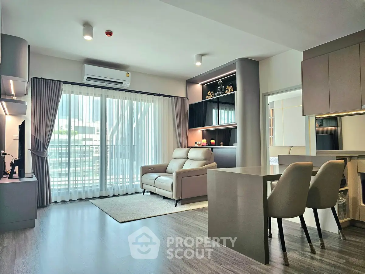 Modern living room with sleek design, featuring a comfortable sofa, stylish dining area, and large windows for natural light.