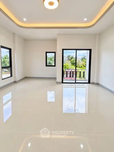 Spacious living room with large windows and balcony access, offering abundant natural light and scenic views.