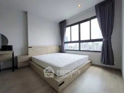Spacious bedroom with large windows offering city views, featuring modern furniture and natural light.