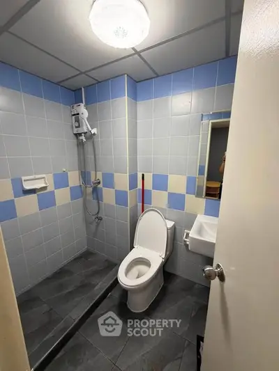Modern bathroom with tiled walls and electric shower in a real estate property.