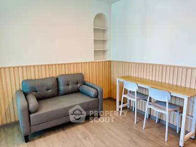 Cozy living room with modern sofa and dining table, featuring stylish wood paneling and shelving.