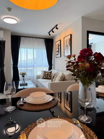 Modern living room with elegant decor and dining area, featuring large windows and stylish furnishings.