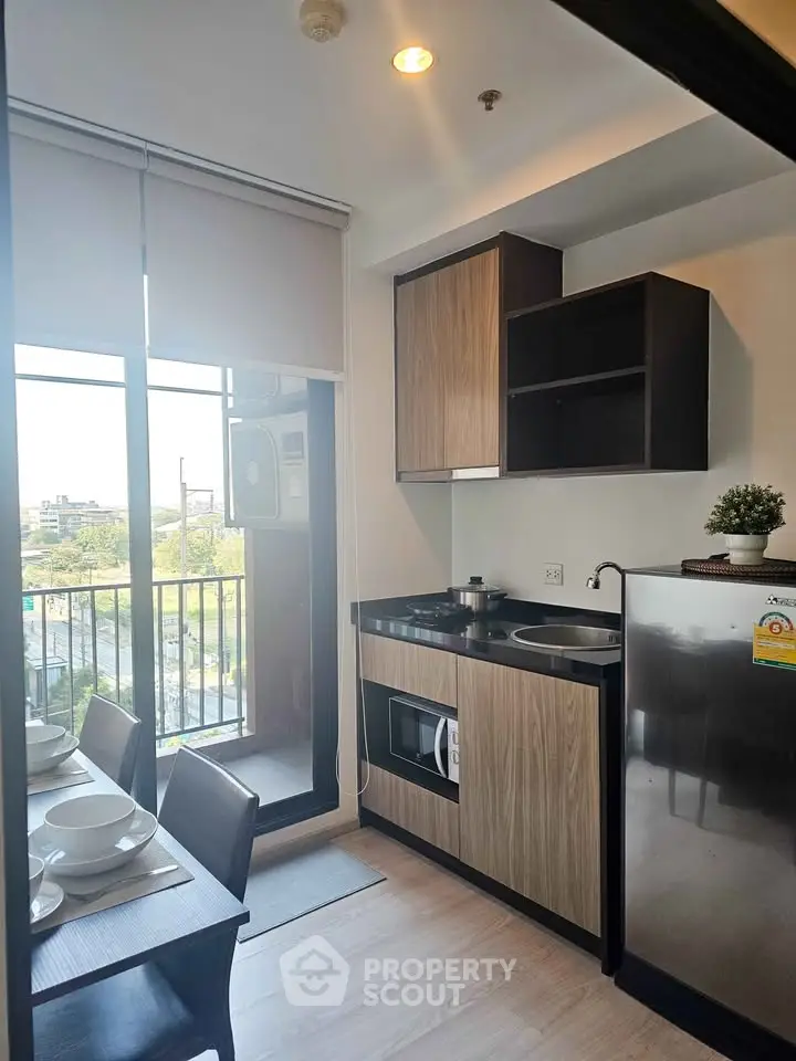 Modern kitchen with balcony view, featuring sleek cabinetry and dining setup.