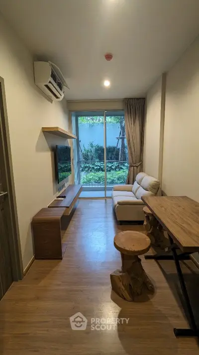 Charming living room with garden view, cozy seating, and modern decor in a compact apartment.