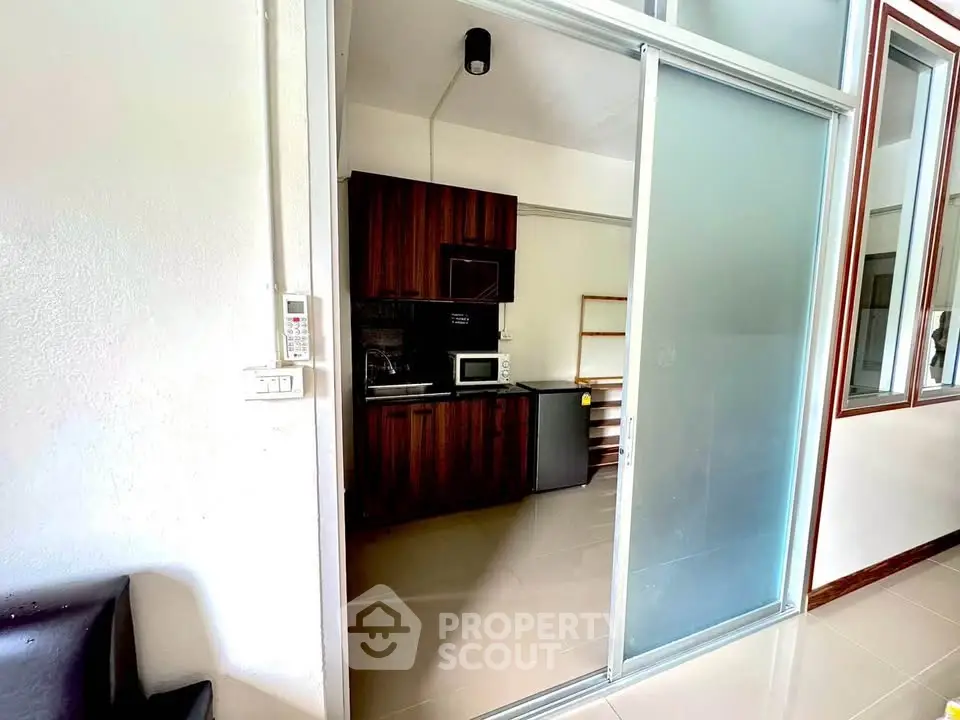Modern compact kitchen with sliding glass door and sleek appliances