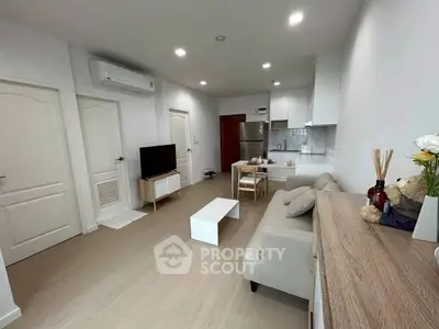 Modern living room with open kitchen, stylish decor, and cozy seating area.