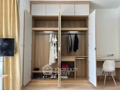Spacious wardrobe in modern bedroom with open doors showcasing ample storage space.