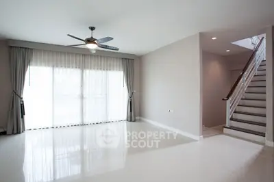 Spacious modern living room with large windows and elegant staircase