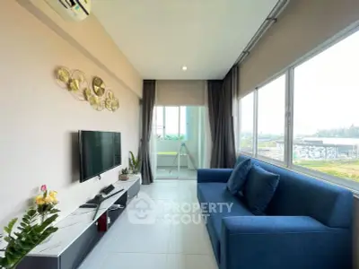 Modern living room with large windows and blue sofa, offering a bright and airy atmosphere.