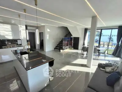 Modern open-plan living room with sleek kitchen and pool view