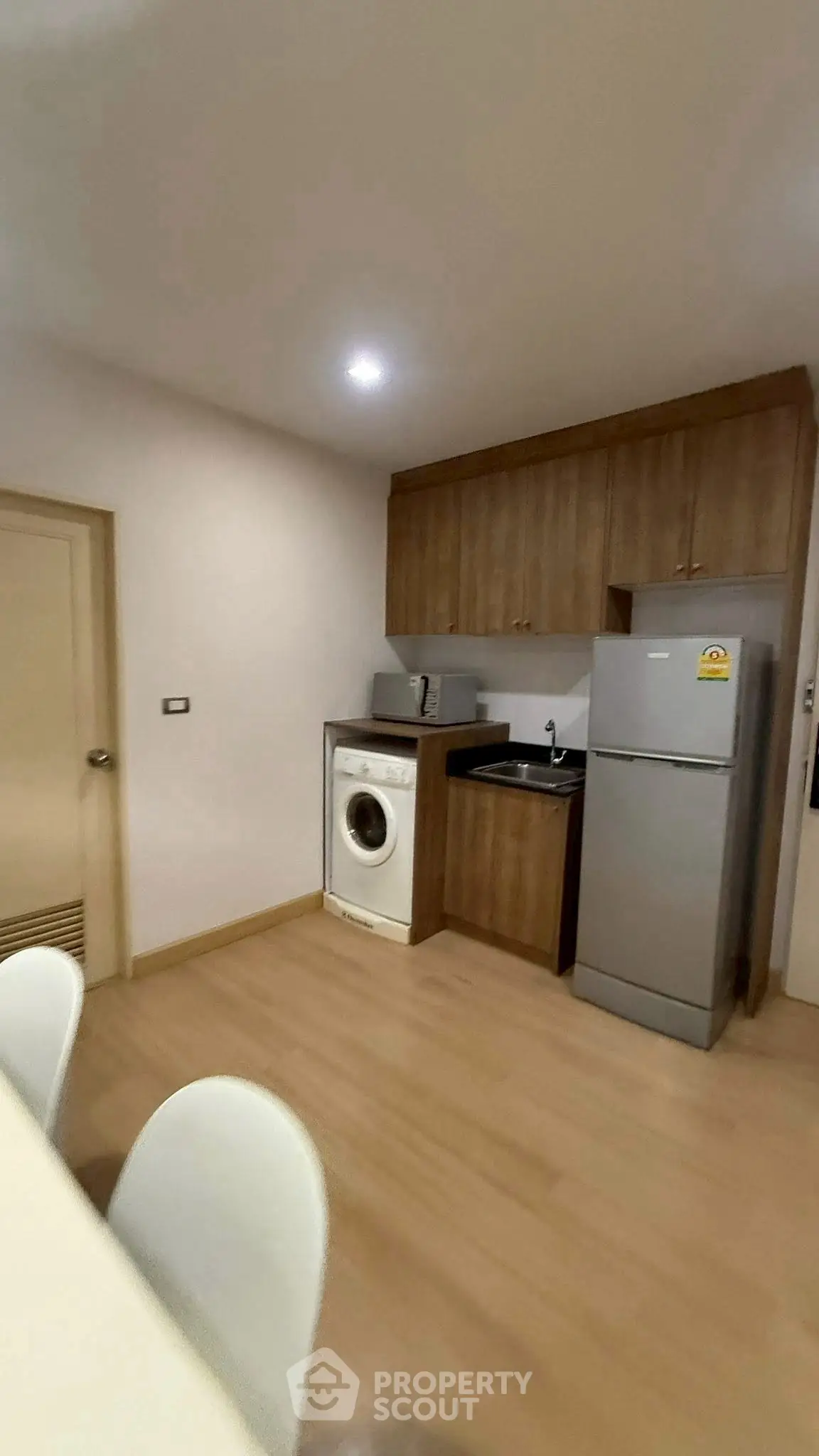 Compact kitchen with washing machine and fridge in modern apartment