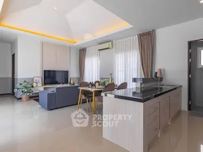 Spacious open-plan living room with modern kitchen and elegant dining area, featuring sleek design and ample natural light.