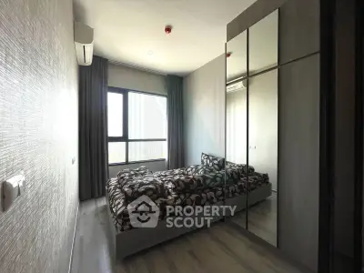 Modern bedroom with mirrored wardrobe and large window offering natural light.