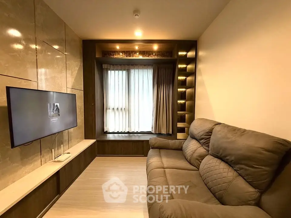 Modern living room with cozy sofa and built-in TV unit, featuring elegant lighting and stylish decor.