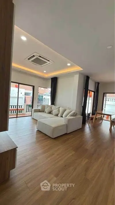 Spacious modern living room with wooden flooring and large windows for natural light.
