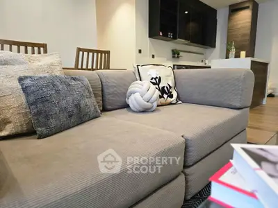 Modern living room with cozy sofa and stylish kitchen in open layout apartment.
