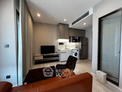 Modern living room with integrated kitchen and washing machine, featuring sleek furniture and contemporary design.