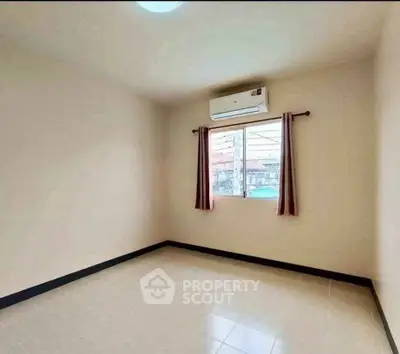 Spacious empty room with air conditioning and window view, perfect for customization.