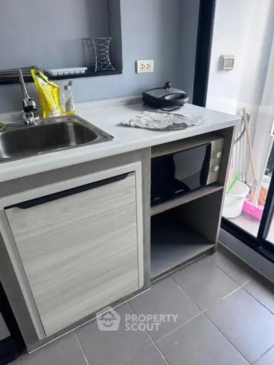 Modern kitchen with sleek countertop, built-in microwave, and under-counter fridge in a compact layout.
