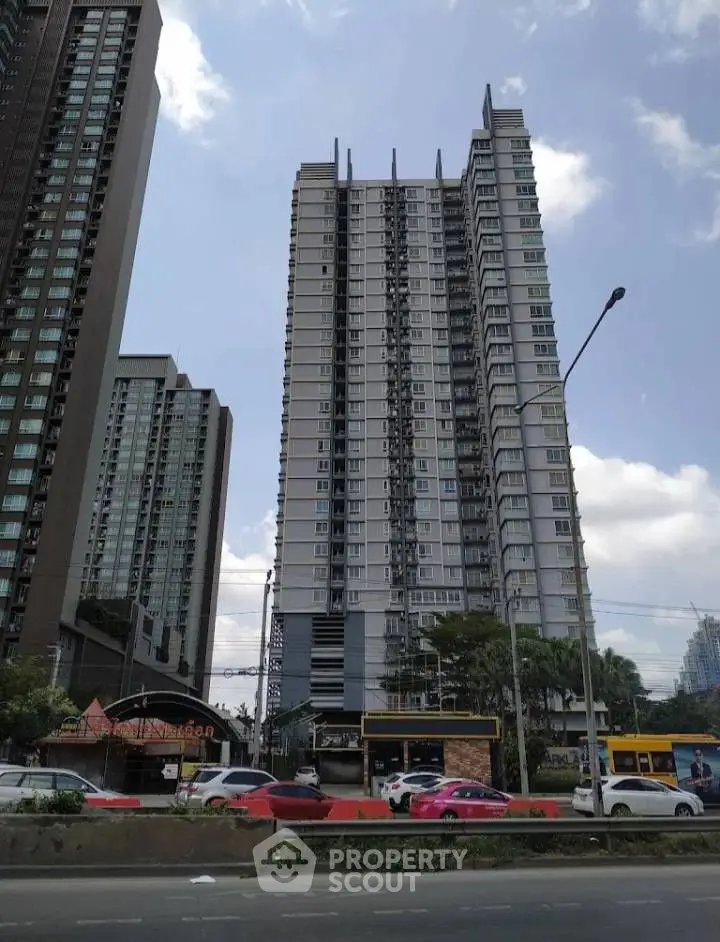 Modern high-rise residential building with urban surroundings and clear sky.