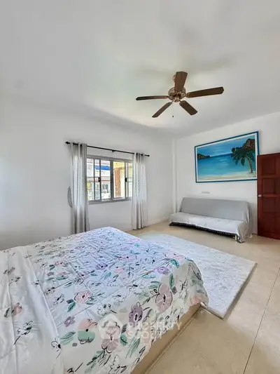 Spacious bedroom with ceiling fan and large window in a modern home.
