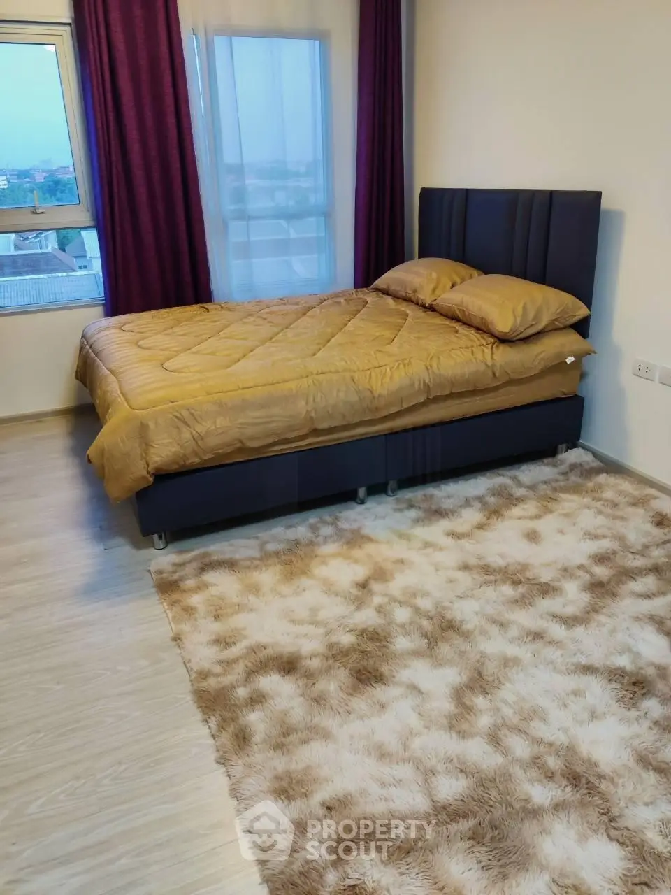 Cozy bedroom with plush carpet and modern bed in a well-lit apartment.