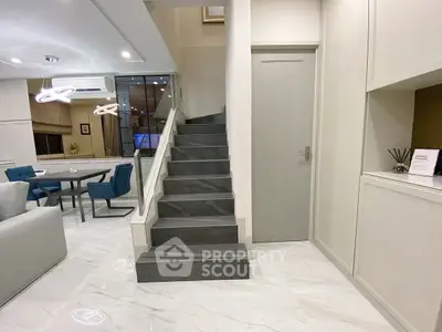 Modern duplex interior with elegant staircase and open living area featuring stylish furniture.