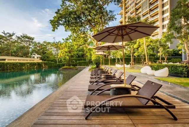 Luxurious poolside area with sun loungers and umbrellas in a modern residential complex.