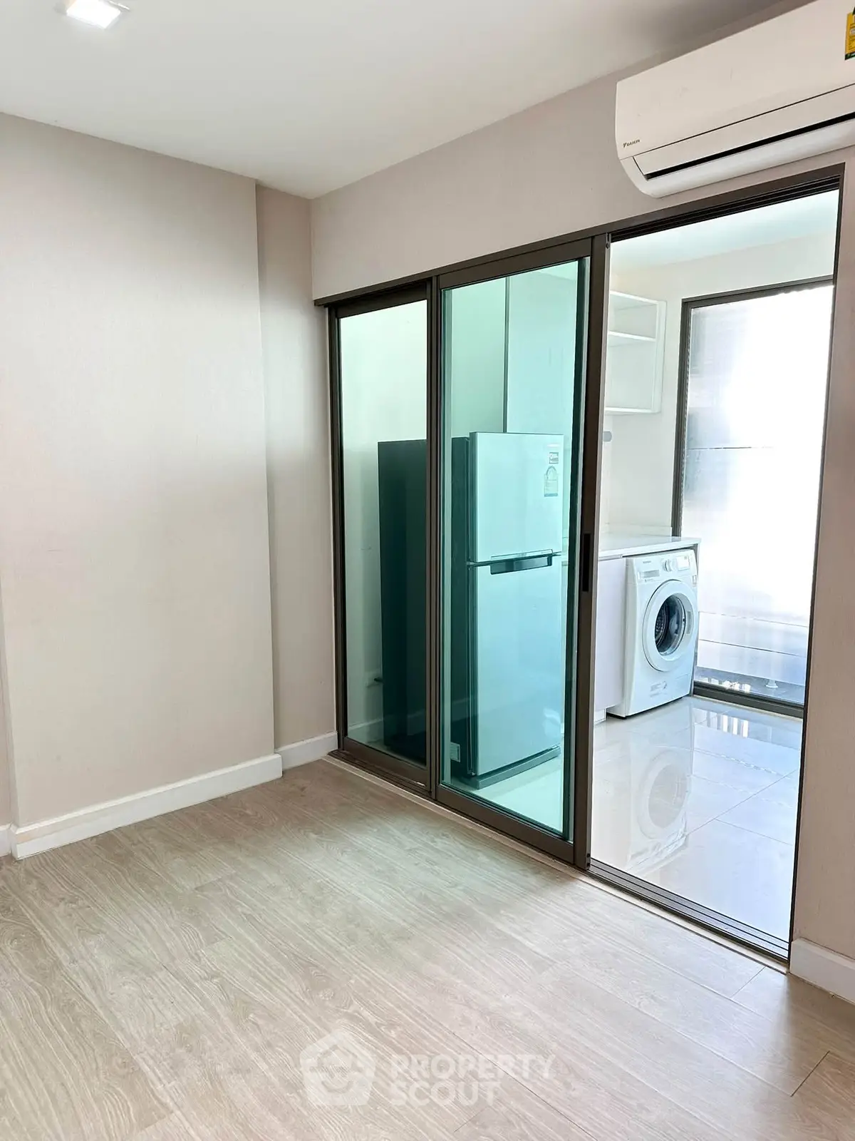 Modern apartment with sliding glass doors, featuring a washing machine and refrigerator in a bright utility area.