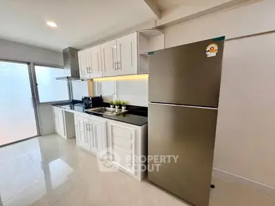 Modern kitchen with sleek cabinets and stainless steel fridge in bright apartment.