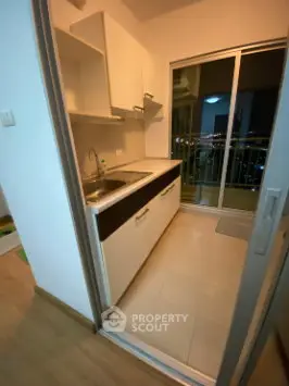 Modern kitchen with sleek cabinetry and balcony view in urban apartment