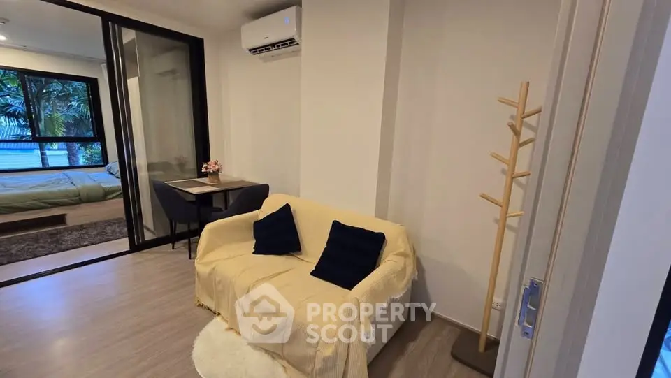 Cozy living room with sofa, air conditioning, and view into bedroom