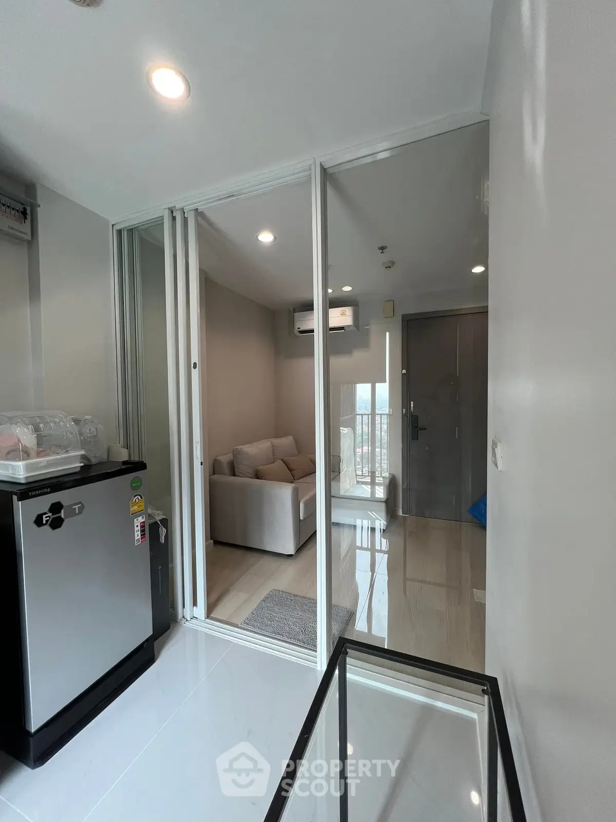 Modern apartment interior with glass partition and compact kitchen area