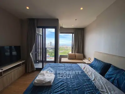 Modern bedroom with city view and balcony access in a high-rise apartment.