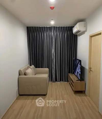 Cozy living room with modern sofa, TV, and air conditioning in a compact space.